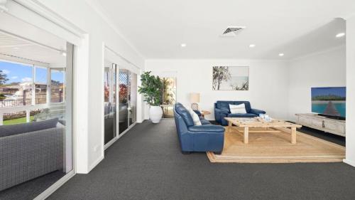 a living room with a blue couch and a table at Hibbard Waterfront Escape in Port Macquarie