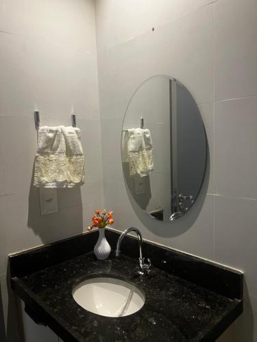 a bathroom with a sink with a mirror and towels at Belize flat praia de Intermares in Cabedelo
