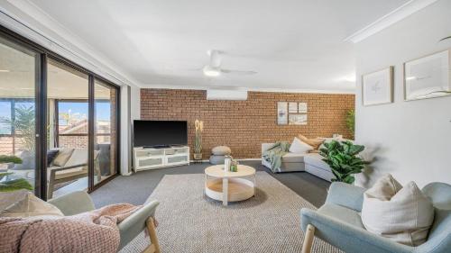 a living room with a couch and a tv at 9 Matthew Flinders Drive in Port Macquarie