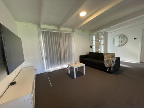 a living room with a black couch and a table at Peaceful 3BR Family Home with free Parking and Garden Oasis in Bayswater