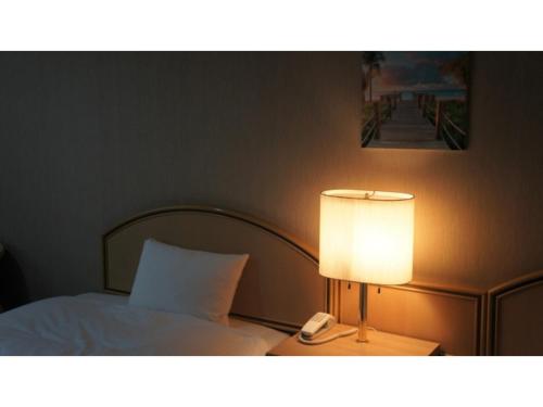 a bedroom with a bed with a lamp and a phone at Utsunomiya Inter Resort Hotel - Vacation STAY 68874v in Utsunomiya