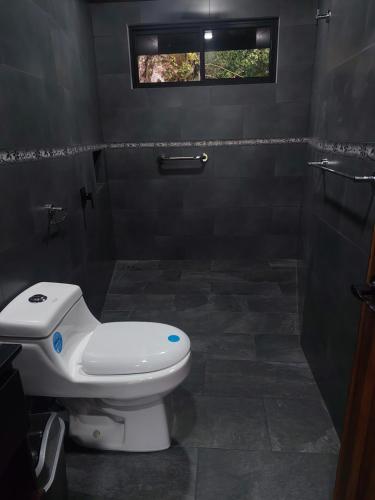Un baño con inodoro y ventana. en Villa Centinela, en Monteverde