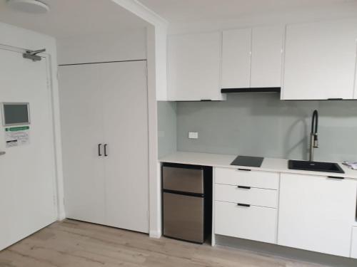 a white kitchen with a sink and a refrigerator at Napoleon On Kent in Sydney