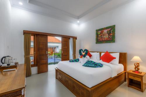 een slaapkamer met een groot wit bed met rode en blauwe kussens bij Memela Bungalow in Nusa Penida