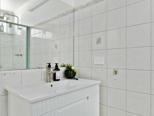 ein weißes Badezimmer mit Waschbecken und Spiegel in der Unterkunft Blue Lotus Riverfront Villas Nelligen in Nelligen