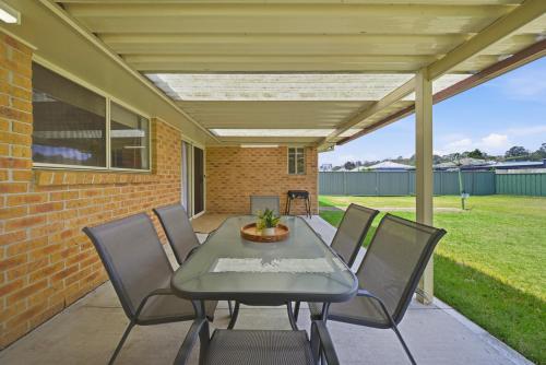 a patio with a table and chairs and a brick wall at Bellbird Willow Hunter Escape by Nature & Winery in Bellbird
