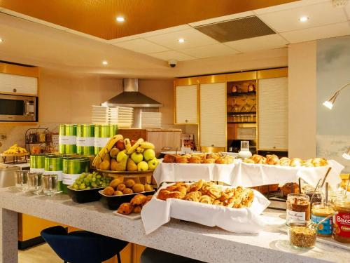 Un buffet con muchos tipos diferentes de comida en un mostrador. en Mercure Rouen Centre Cathédrale, en Rouen