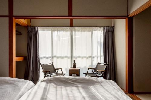 a bedroom with two chairs and a bed and a window at hotel 翡翠 in Ise
