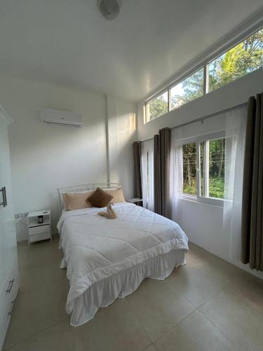 a white bedroom with a bed and a window at Agape Suites-Room 4- 1st Floor in Soufrière