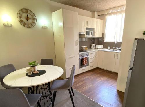 a kitchen with a table and a clock on the wall at Central Wollongong Apartment - 2 bedrooms in Wollongong