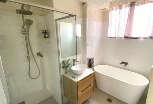 a bathroom with a tub and a sink and a shower at Central Wollongong Apartment - 2 bedrooms in Wollongong