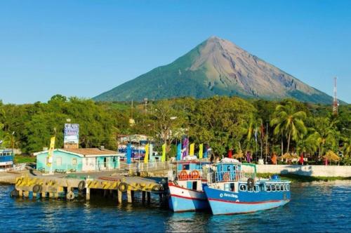 two boats docked at a dock with a mountain in the background at Hostal tortuga viajera in Moyogalpa