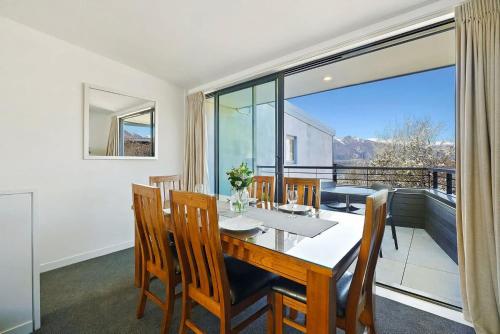 a dining room with a table and chairs and a balcony at The Alps Apartment in Queenstown