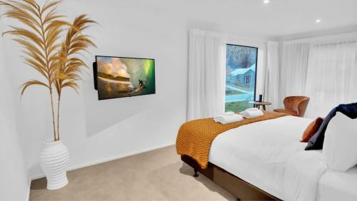a white bedroom with a bed and a window at The Gold Mine in Arrowtown