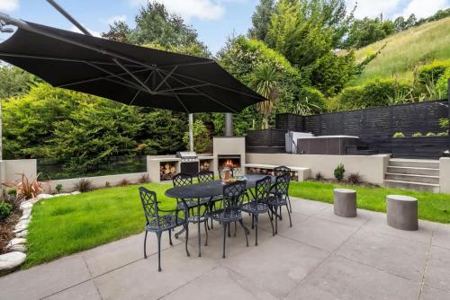 a patio with a table and chairs and an umbrella at The Stowaway in Queenstown