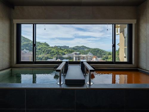 a swimming pool with a large window in a building at Arima Onsen Takayamaso Hanano in Kobe