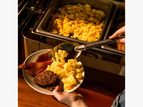 una persona che tiene un piatto di cibo per la colazione in un forno di Trailborn Grand Canyon, Outdoor Collection by Marriott Bonvoy a Williams