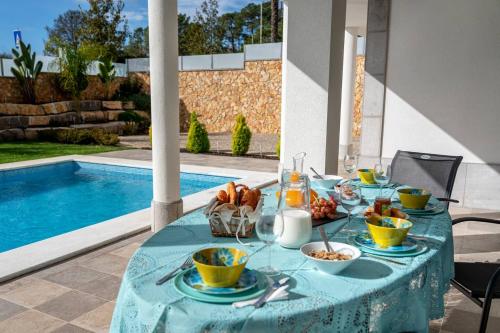 a table with food on it next to a pool at Luxury Vau Beach Villa with Private Heated Pool in Portimão