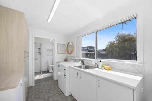 ein weißes Badezimmer mit Waschbecken und Fenster in der Unterkunft Nans at Northy - modern river cottage in North Haven