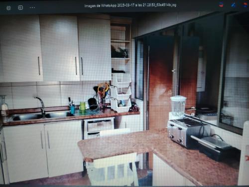 a kitchen with white cabinets and a counter top at Mi casa es tu casa in La Serena