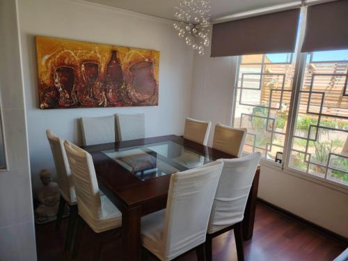 a dining room table with white chairs and a painting at Mi casa es tu casa in La Serena
