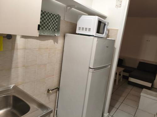 a microwave on top of a refrigerator in a kitchen at RELAX Privacy in Sarcelles