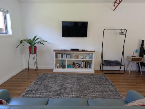 a living room with a tv and a blue couch at Langleys Port Campbell Hobby Farm in Port Campbell