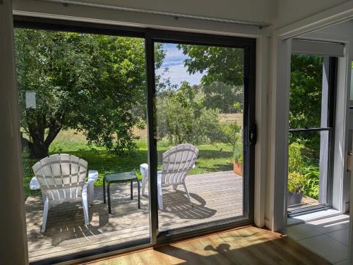 a screened in porch with two chairs and a table at Langleys Port Campbell Hobby Farm in Port Campbell