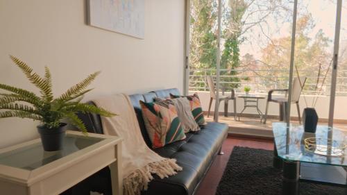 un salon avec un canapé en cuir noir et une table dans l'établissement Norus Providencia, à Santiago