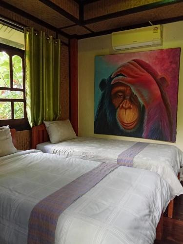 two beds in a room with a painting on the wall at Ouychai Home stay resort in Chiang Mai