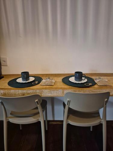 a table with two cups and two chairs at Studio Privativo a 3 min Centro c Ar Condicionado in Uberlândia