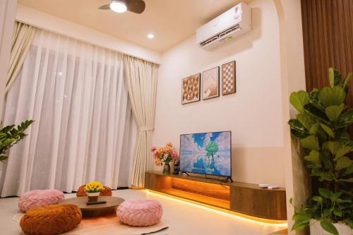 a living room with a television and pink ottomans at Beer Home Apartment - Huế Free Pool and Gym in Hue