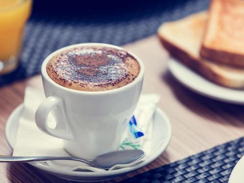 a cup of coffee on a plate on a table at Mercure Welcome Melbourne in Melbourne
