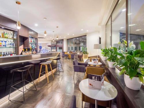 a restaurant with a bar with chairs and plants at Mercure Roma Piazza Bologna in Rome
