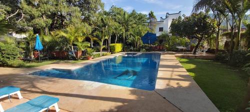 a swimming pool in a yard with two blue chairs at Posada Sarita in Tepoztlán