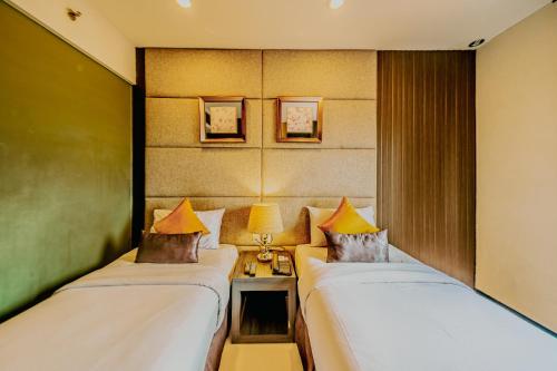 a room with two beds and a table with lamps at Serela Merdeka by KAGUM Hotels in Bandung