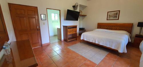a bedroom with a bed and a dresser and a television at Posada Sarita in Tepoztlán