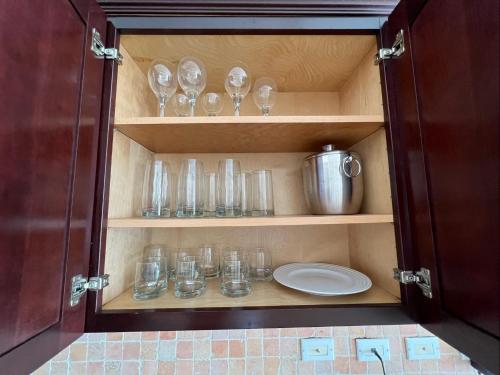 Ocean Bliss: Balcony & Pools & Peloton Bike! في Lowlands: خزانة مليئة بالأكواب وبداخلها طبق