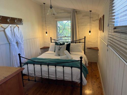 a bedroom with a bed with white sheets and a window at Gladstone House in Beechworth
