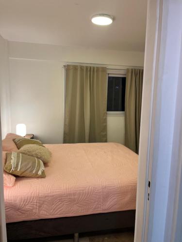 Departamento ideal encantador en morón centro في مورون: غرفة نوم بها سرير بملاءات وردية ونافذة