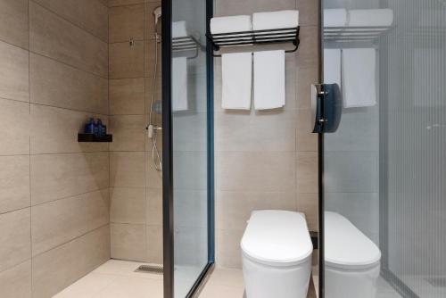 a bathroom with a toilet and a glass shower at Hanting Hotel Chongqing Lianglukou Caiyuanba in Chongqing