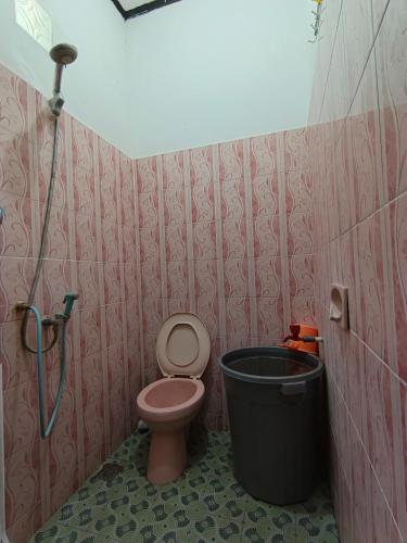 a bathroom with a toilet and a trash can at Labore Homestay in Waha