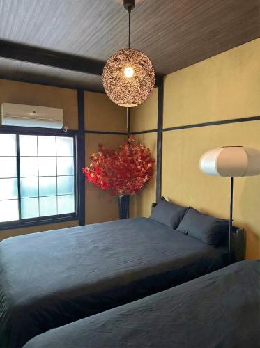 a bedroom with a bed and a vase with a red plant at TRAVELERZ YOKOHAMA Demon Slayer House in Kikuna