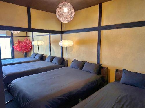 a bedroom with three beds and a chandelier at TRAVELERZ YOKOHAMA Demon Slayer House in Kikuna