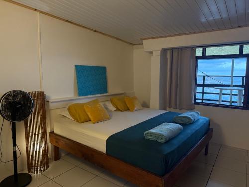 a bedroom with a bed with yellow and blue pillows at Ave Surfing House in Mahina