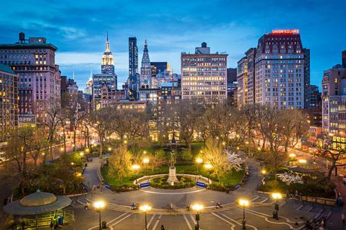 a city skyline at night with a fountain in a park at Oasis Retreat - Cozy studio in Union Square in New York