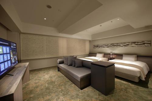 una camera con due letti, un divano e una TV di ORIENTAL HOTEL KYOTO ROKUJO a Kyoto