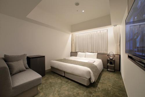 una camera con letto, sedia e TV di ORIENTAL HOTEL KYOTO ROKUJO a Kyoto