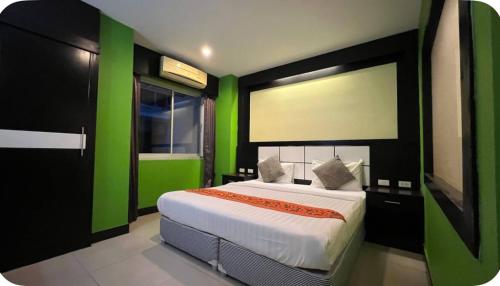 a bedroom with a large bed with green walls at Star House Patong in Patong Beach