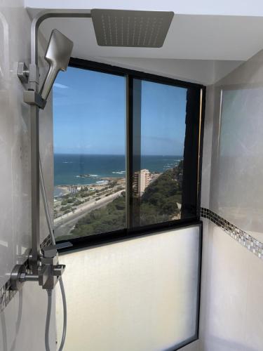 a window in a room with a view of the ocean at Oceanfront Playa Grande 10 min Airport Maiquetia Aeropuerto in Maiquetía